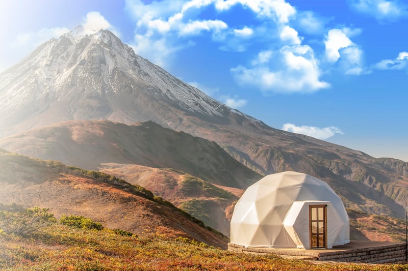 A lone glamping tent with a beautiful snow capped mountain as a backdrop
