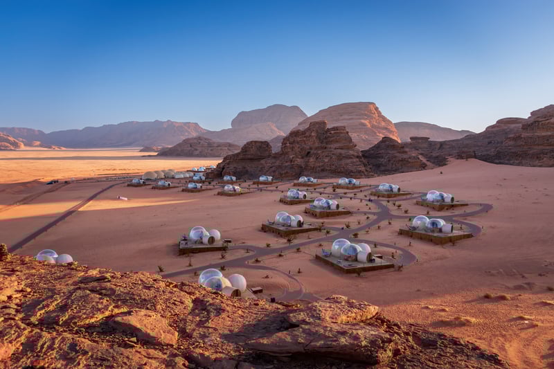 View of Suncity Camp from atop a cliff in the desert valley of Wadi Rum, Jordan, one of the best glamping sites in the world.