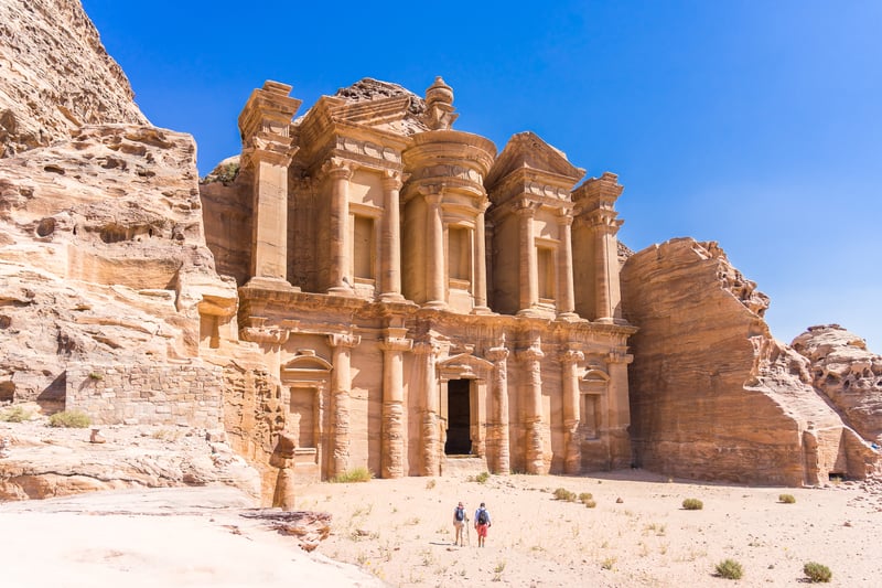 A couple of tourists walking towards the ancient architectural wonder of Petra, Jordan 