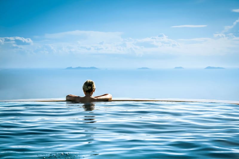 Woman in an infinity edge pool at a wellness center with sea in the background