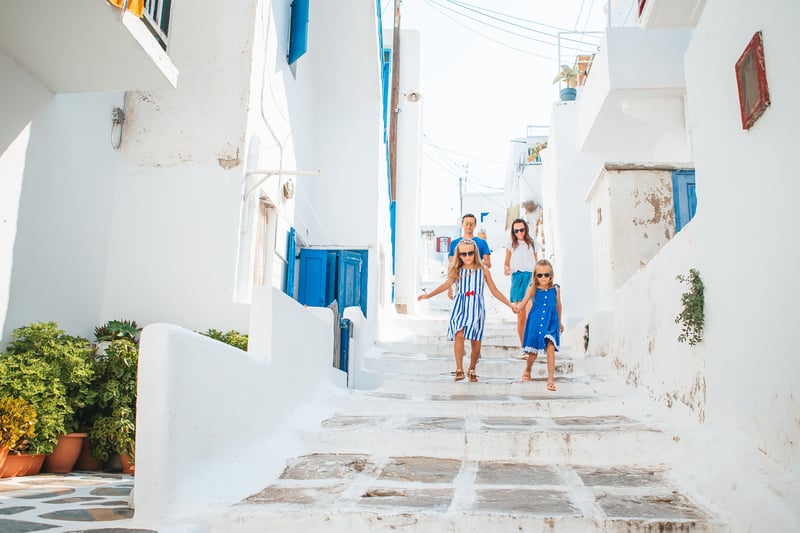 A traveling family walking the steps of a Greek Island Village