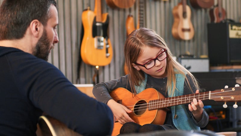 A man teaching his passion - guitar lessons to a young female student with purpose
