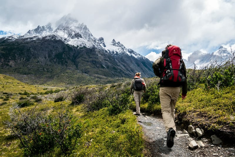 A couple hiking towards a snow-capped mountain