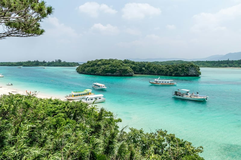 Boats anchored in tropical bay with islands in blue zone hotspot Okinawa, Japan 