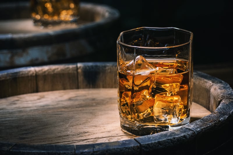 A glass of Glen Grant whisky on the rocks on top of a whiskey barrel