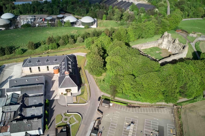 Aerial shot of world-famous Glenfiddich whiskey distillery next to ruins of an ancient castle