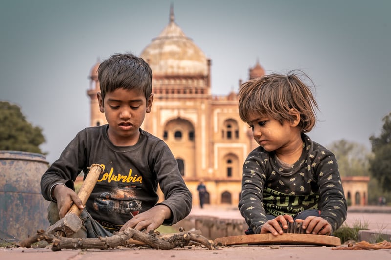 Two Indian street kids playing with a palace in the background symbolising the paradox of global citizenship