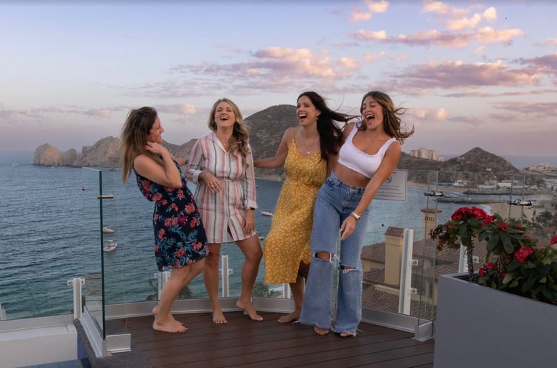 Amanda with three female colleagues laughing on a balcony overlooking Cabo San Lucas.