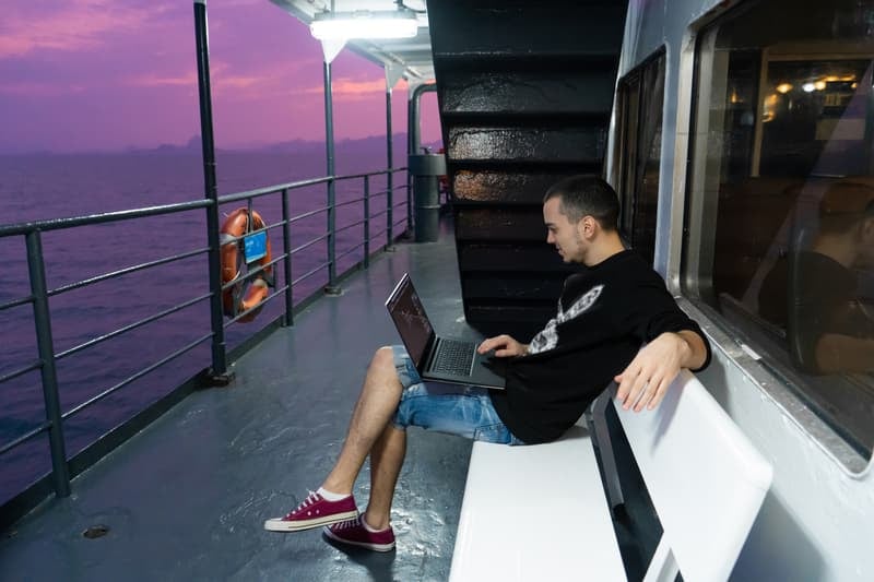 Man working on laptop on the deck of a cruise ship