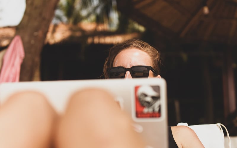 A woman working from her laptop from a tropical location