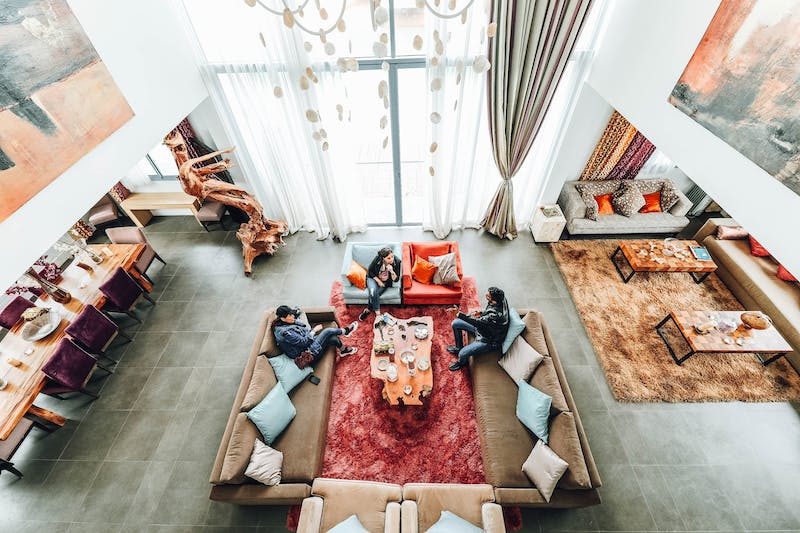 Three people sitting on plush sofas discussing co-ownership arrangement inside a luxury home