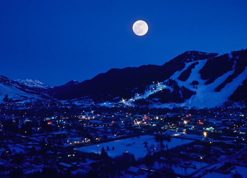 A full moon rises over the Town of Jackson in the southern end of Jackson Hole, Wyoming with Snow King Ski Resort in the background.