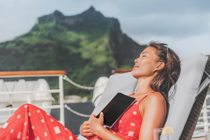 Attractive woman having a siesta on a luxury residential cruise ship with tropical mountain in the background