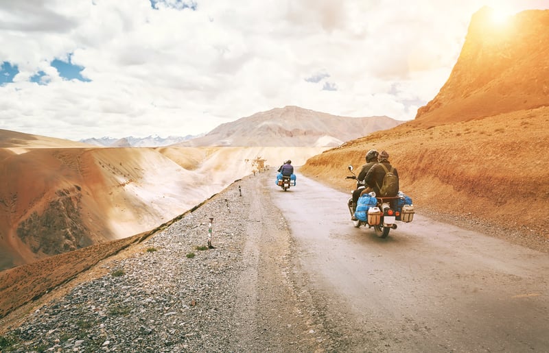 Travelers on motorbikes slow traveling through a mountains desert road