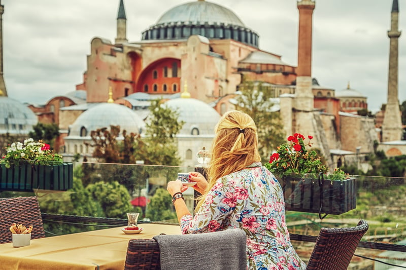 Solo female traveler drinking tea while admiring the Blue Mosque in Turkey