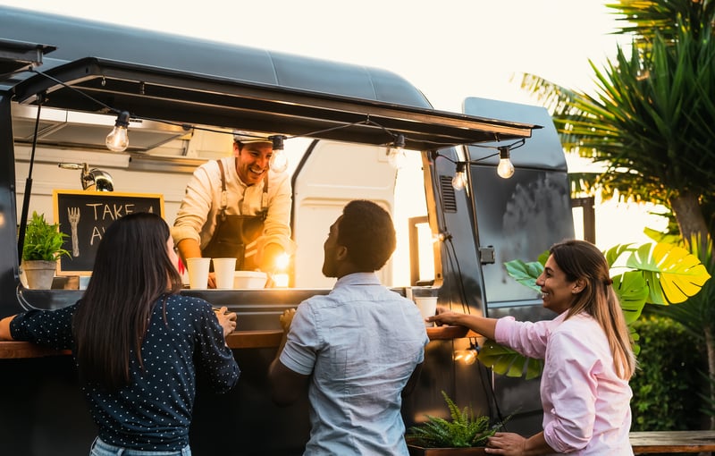 Young people buying meal from street food truck - Modern business and take away concept