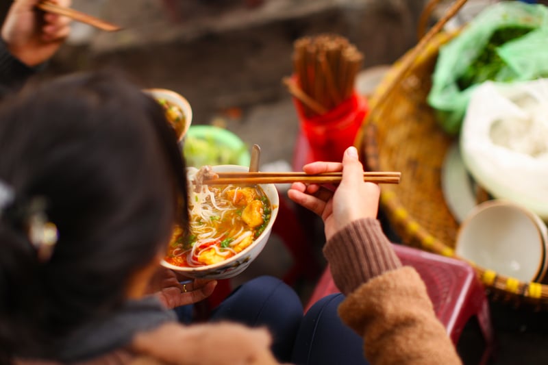 Woman eating Bun cha or pho soup, street food in Vietnam