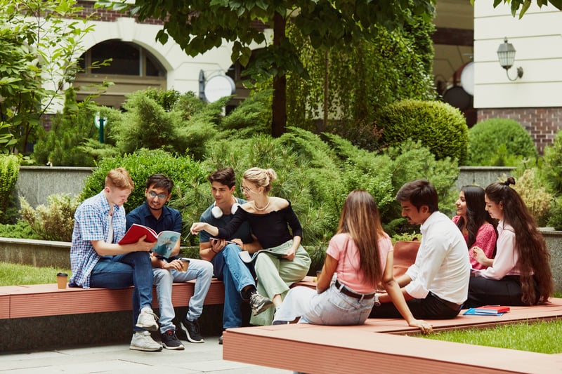 Teenagers sitting around in college as part of a world schooling community courtyard wishing 