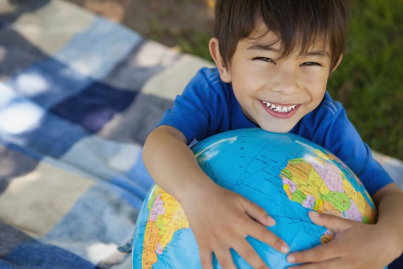 Close-up portrait of a cute young boy holding globe at the park