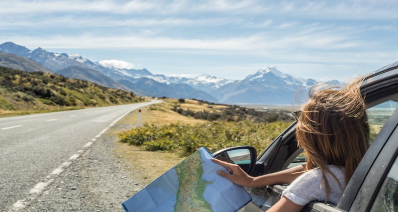 Young girl stopping her car to look on a map to start her roadtrip.
